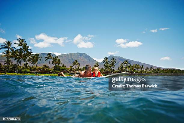 father and son paddling out on surfboard - maui stock pictures, royalty-free photos & images