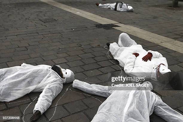 Women, white-dressed and wearing a white mask, lie on the ground on November 25, 2010 in Paris, during a rally organised by rights group 'Ni putes,...