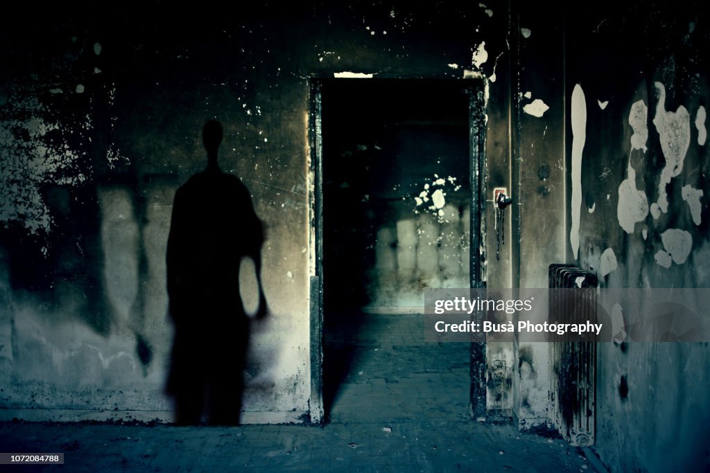 Scary scene with spooky shadow in a dark room of an abandoned building