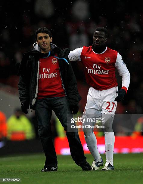Emmanuel Eboue of Arsenal apprehends a pitch invader during the Carling Cup quarter final match between Arsenal and Wigan Athletic at the Emirates...