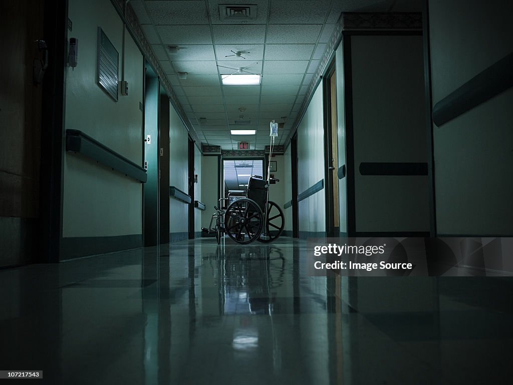 Empty wheelchair and intravenous drip in hospital corridor