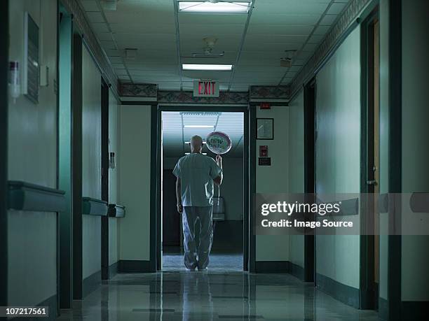 male nurse holding helium balloon celebrating newborn baby - working late stockfoto's en -beelden