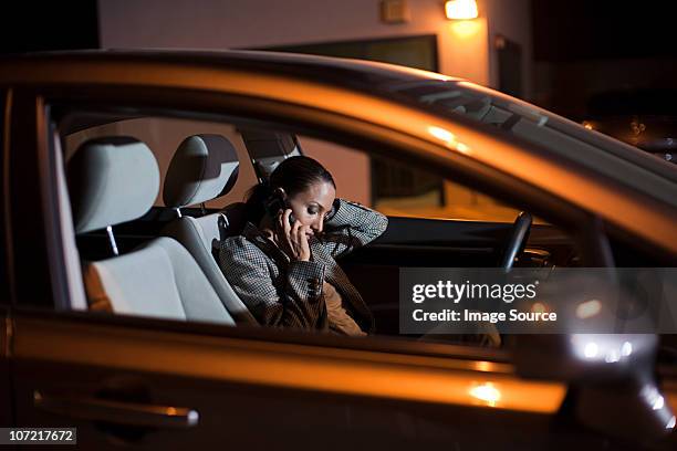 mujer de negocios mediante teléfono móvil en el coche en noche - una mujer de mediana edad solamente fotografías e imágenes de stock