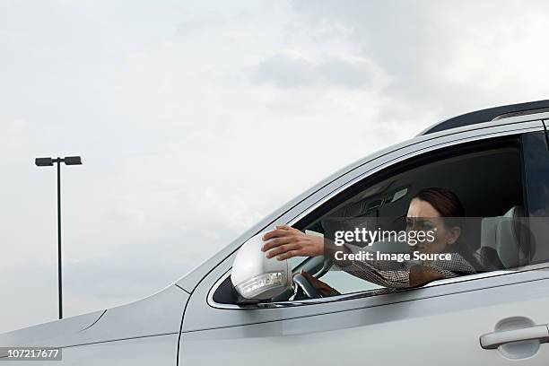 businesswoman driving car, adjusting wing mirror - side view mirror stockfoto's en -beelden