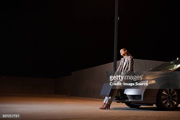 businesswoman with briefcase in car park at night - car hood stock pictures, royalty-free photos & images
