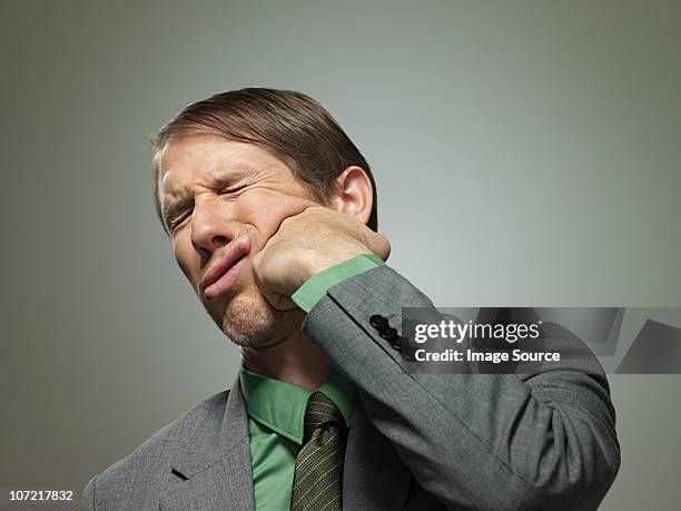 mid adult businessman punching himself in face, portrait - slugs stockfoto's en -beelden