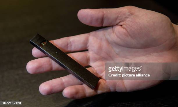 December 2018, Hamburg: A man holds an e-cigarette of the manufacturer "Juul" in his hand. "Juul" is the market leader for e-cigarettes in the USA...