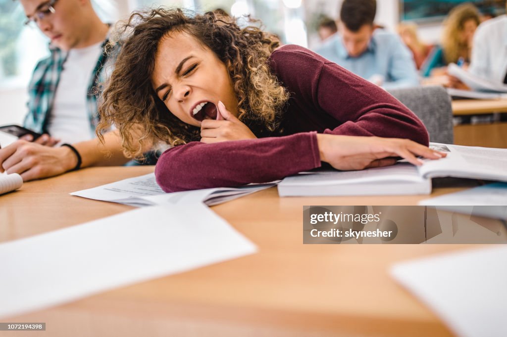 Aluna cansada bocejando em uma classe em sala de aula.