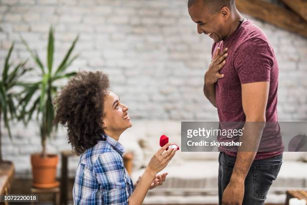 felice donna afroamericana che propone al suo ragazzo a casa. - black women engagement rings foto e immagini stock