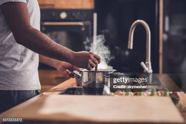 unrecognizable man making lunch in the kitchen and stirring soup. - boiling steam stock pictures, royalty-free photos & images