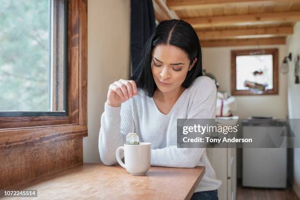 young woman at home in her tiny house - ティーバッグ ストックフォトと画像