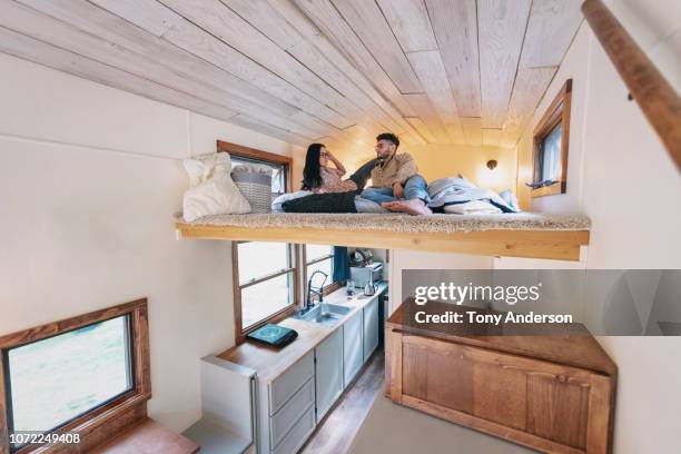 young couple in bedroom loft of tiny house - afgesloten ruimte stockfoto's en -beelden