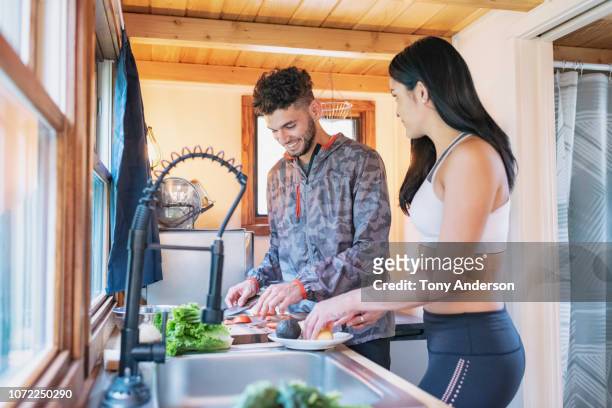 young couple preparing meal in kitchen of tiny house - roupa desportiva imagens e fotografias de stock