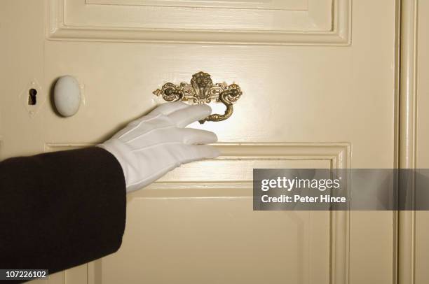 white gloved hand of uniformed man on door handle - hotelpage stock-fotos und bilder