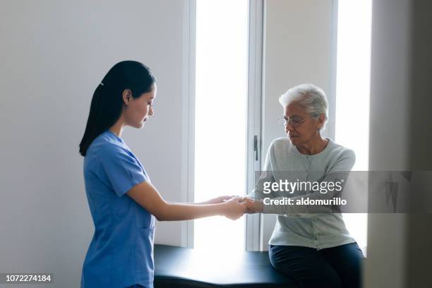 female nurse holding hands of senior patient - nurse praying stock pictures, royalty-free photos & images
