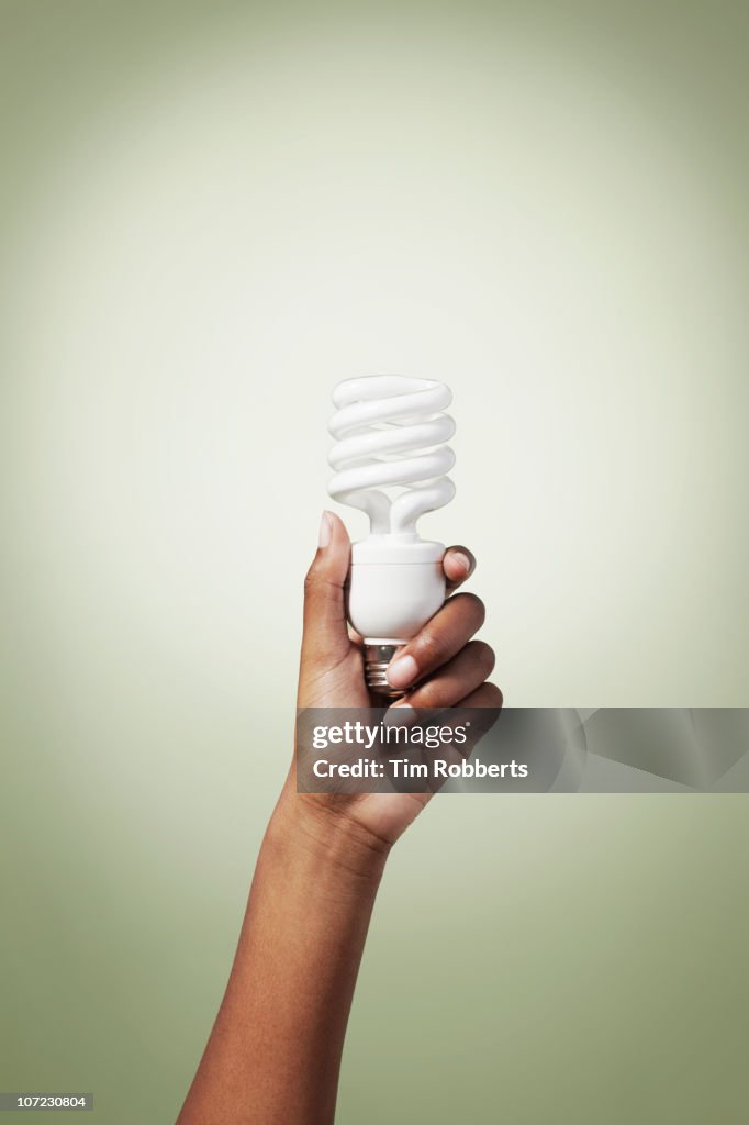 Young woman holding energy efficient light bulb.