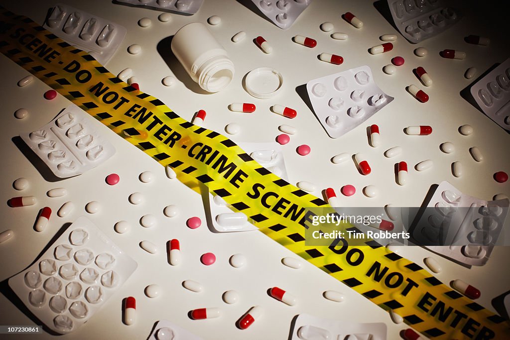 Empty pill packets and pills with crime scene tape