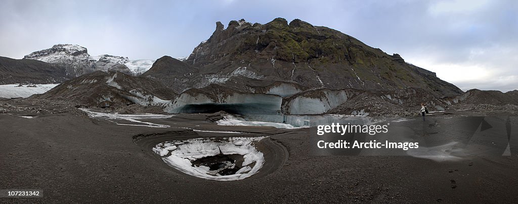 Woman viewing ash covered glacier, Iceland