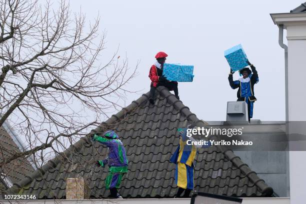 People dressed as traditional characters known as Zwarte Piet or Black Pete, performs atop a roof top ahead of the arrival of Sinterklaas November 24...
