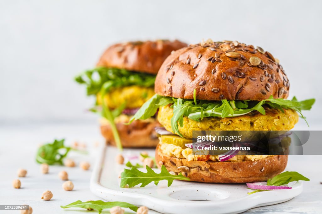 Hamburguesas de garbanzos vegano con rúcula, pepinos conservados en vinagre y hummus, copia espacio.