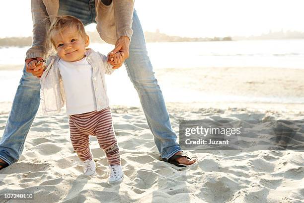 mother helping toddler to take first steps - first steps stock-fotos und bilder