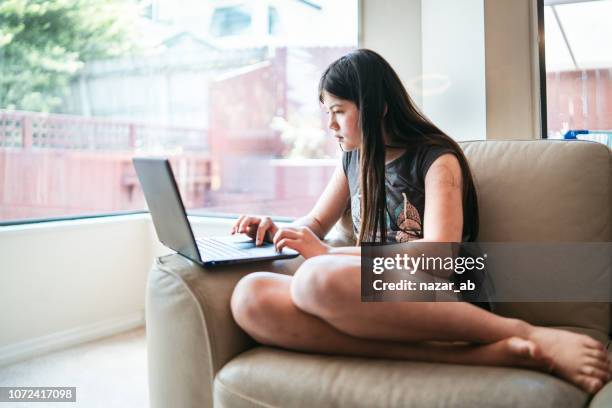 eurasian girl at home on laptop. - classroom laptop stock pictures, royalty-free photos & images