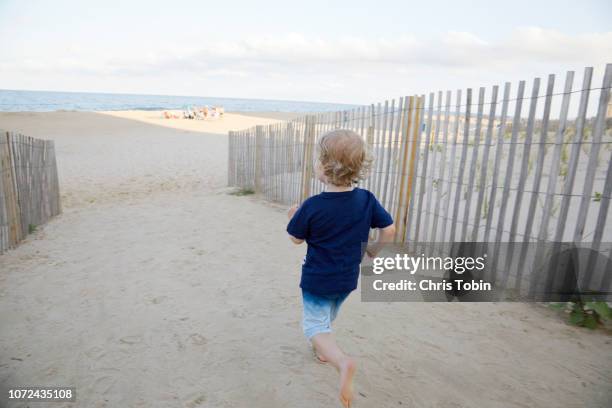 young boy running down the dune towards the beach - ocean city maryland stock pictures, royalty-free photos & images