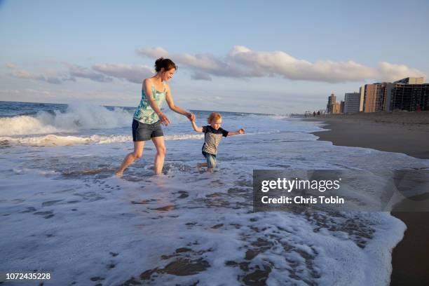 mother and young boy holding hands and wading at the beach - ocean city maryland stockfoto's en -beelden