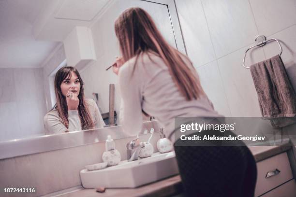 sensual young female applying lipstick in front of a bathroom mirror - woman lipstick rearview stock pictures, royalty-free photos & images