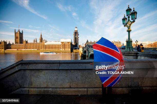 Souvenir stall holder opens a Union Flag umbrella as he arranges his stock opposite the Houses of Parliament on the southern bank of the River Thames...