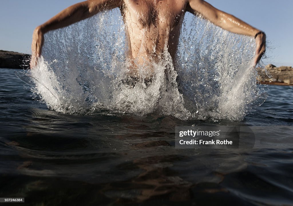 Young sportive man jumping out of the water