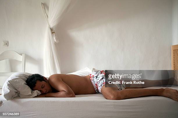 man sleeps on a bed in a summer house  - boxershorts stock-fotos und bilder