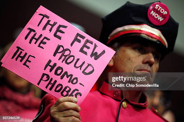 Demonstrator from Code Pink for Peace hold up a sign during a hearing of the Senate Armed Services Committee about the military's "don't ask, don't...