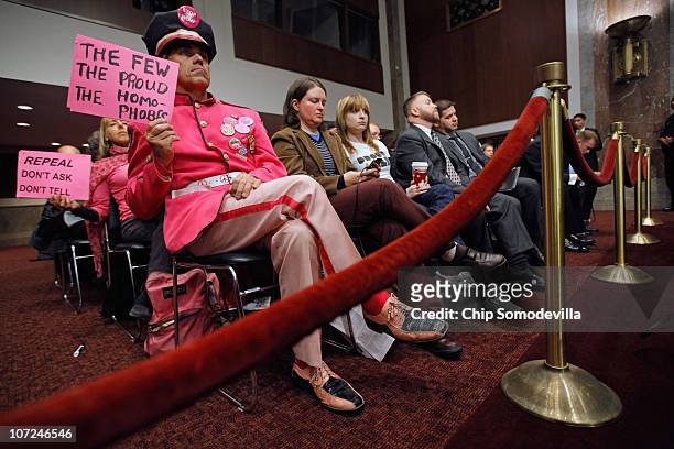 Demonstrators from Code Pink for Peace hold up signs during a hearing of the Senate Armed Services Committee about the military's "don't ask, don't...