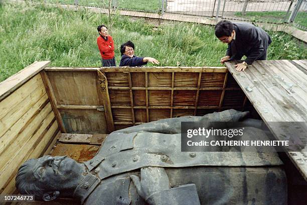 Mongolian workers look at a statue of Stalin on July 26, 1990 in Mongolia that has been in storage since February when it was removed from in front...