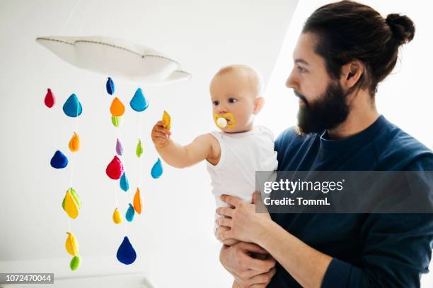 baby holding onto dad while playing wth mobile - mobile imagens e fotografias de stock