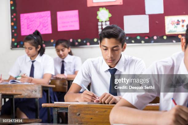 male student in classroom writing in notebook - stock image - school exam imagens e fotografias de stock