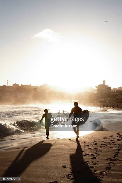 two surfers walking along the beach - sydney beaches stock-fotos und bilder