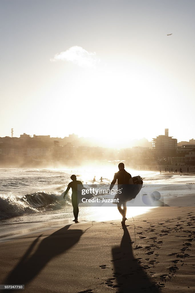 Two surfers walking along the beach