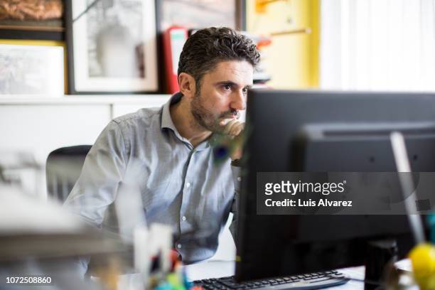 textile shop owner working at his desk - job search stockfoto's en -beelden