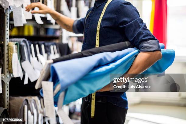 fashion designer picking the fabric rolls from the rack - fabric rolls photos et images de collection