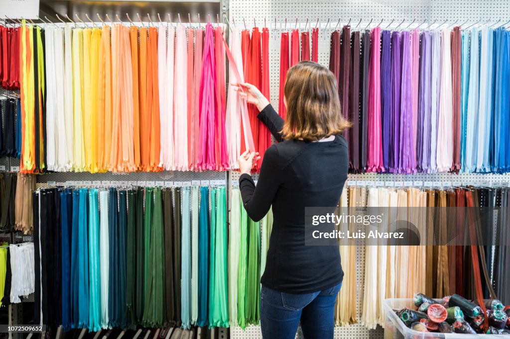 Woman examining colorful zippers on rack in store