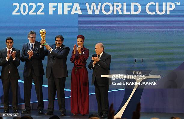 Qatar's Emir Sheikh Hamad bin Khalifa al-Thani raises the World Cup trophy as he stands with his wife Sheikha Moza, their son Sheikh Mohammed,...