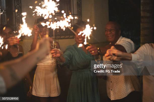 family and friends celebrating new year party with sparkler at home - black family reunion stock pictures, royalty-free photos & images
