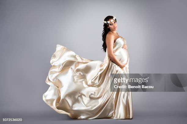 pregnant woman in a beige satin dress - satijnen jurk stockfoto's en -beelden