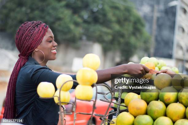smiling young woman takes her money in the hand of the fruit seller. - elfenbenskusten bildbanksfoton och bilder