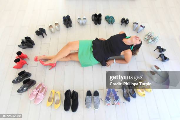 brunette woman at her home surrounded by shoes. - shoe collection stockfoto's en -beelden