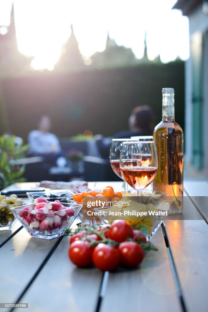 Holiday summer brunch party table outdoor in house backyard with appetizer, glass of rose wine, fresh drink and organic vegetables.