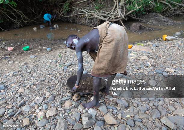 Suri tribe girl doing gold panning in a river, Omo valley, Kibish, Ethiopia on October 23, 2018 in Kibish, Ethiopia.