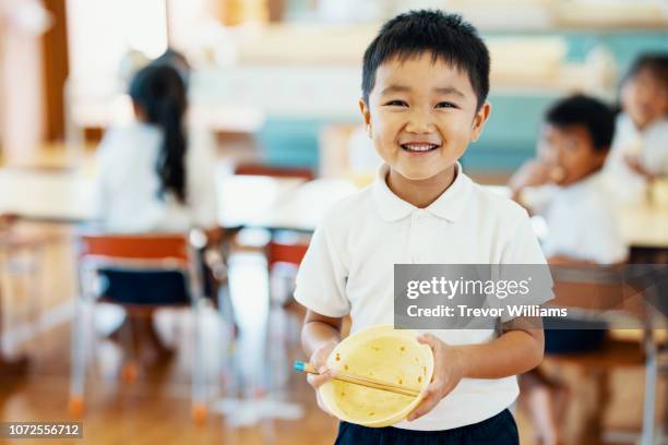 young boy showing his empty bowl after eating school lunch at preschool - 子供　日本人　笑顔 ストックフォトと画像